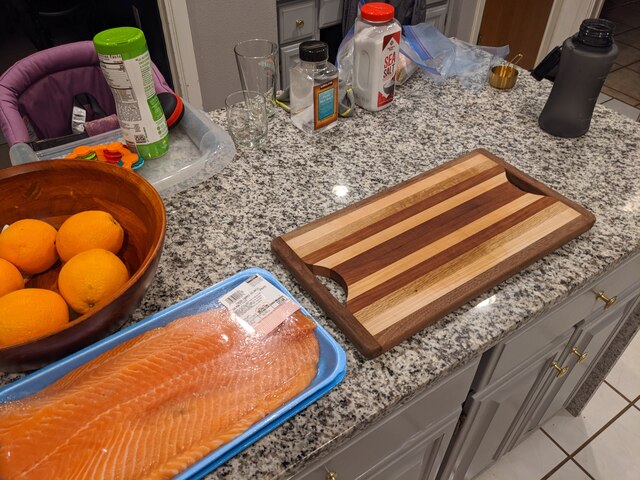 A beautiful, large salmon filet in its store packaging next to a cutting board