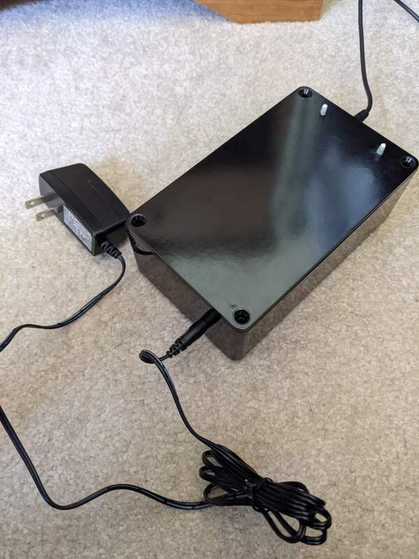 A black project box with wall-wart transformer plugged into one side, and current transformer cable coming out the other.